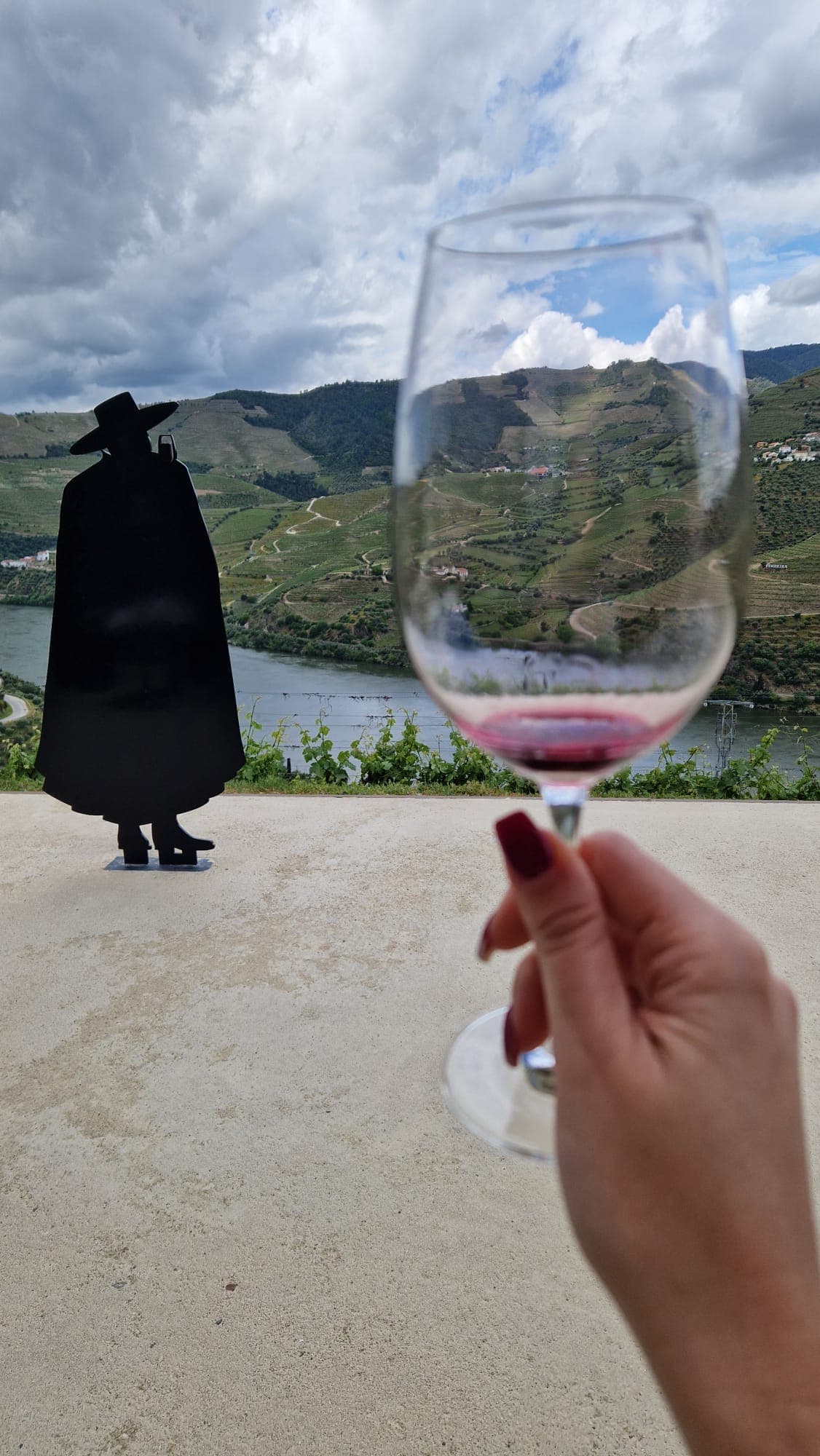 Taça de Vinho do Porto com vista sobre o Douro e figura da Sandeman ao fundo