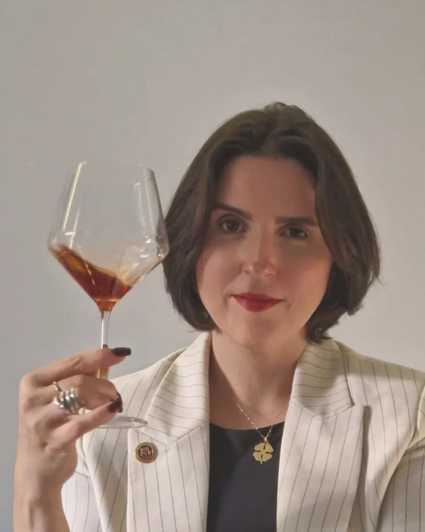 Lívia Belfort com blazer branco segurando uma taça
